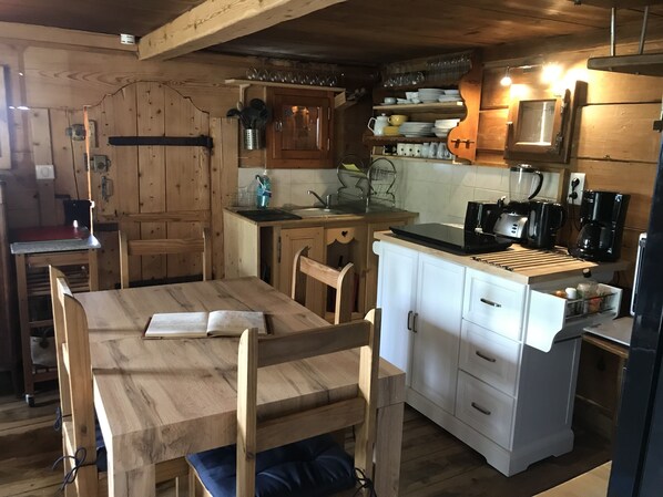 Una cocina funcional con armarios de madera, una mesa de comedor y electrodomésticos básicos.