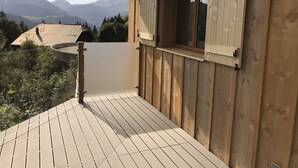 Una terraza de madera con ventanal a un paisaje montañoso.