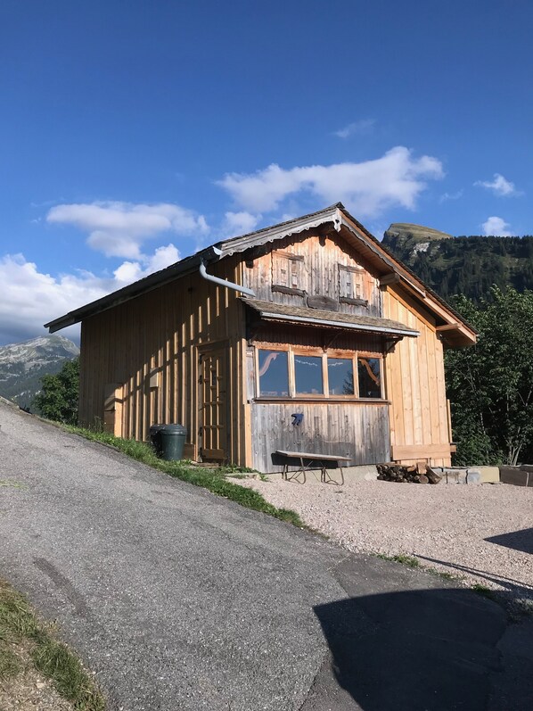 A wooden cabin with a balcony, a bench, and a table outside.
