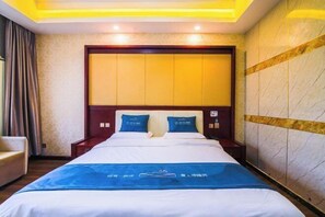 Ein Hotelzimmer mit einem großen Bett, einem Holz-Kopfteil und einer blauen Bettdecke.