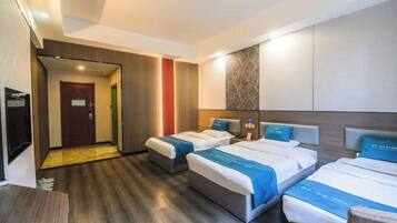 A hotel room with two beds, a wooden floor, a TV, and a door leading to another room.