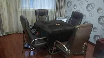 Un salón de conferencias con una mesa negra y sillas de cuero, una pizarra y una ventana con cortinas.