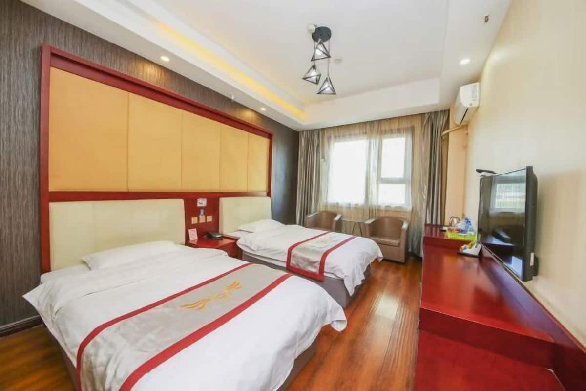 Una habitación de hotel con dos camas, televisión, escritorio y ventana con cortinas.
