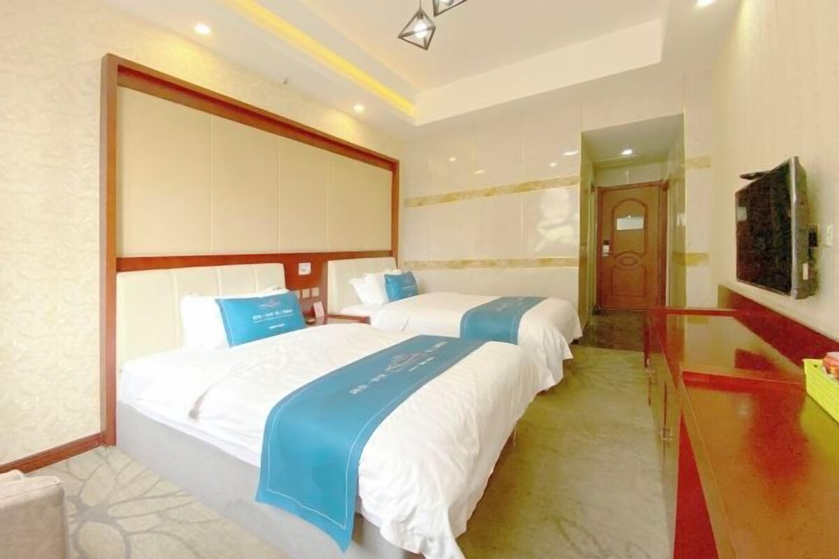 Une chambre d’hôtel avec deux lits, une tête de lit en bois, un mur d’accent rouge et un petit bureau avec un miroir.