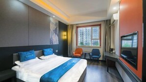 Hotelkamer met een groot bed, een bureau, een televisie en een raam met uitzicht op de stad.