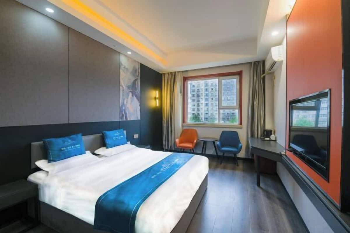 Habitación de hotel con una cama grande, un escritorio, un televisor y una ventana con vistas a la ciudad.