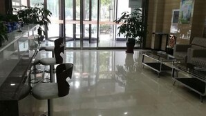 Een moderne lobby met een glazen scheidingswand, zithoek en potplanten.