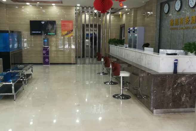 A hotel reception area with a marble counter, a television, and a seating area with bar stools.