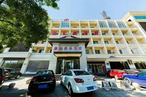 A multi-story hotel with a prominent entrance, several parked cars, and a clear sky.