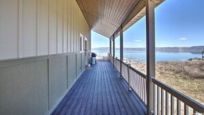 Eine überdachte Holzterrasse mit Blick auf einen See und entfernte Berge.