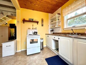A kitchen with white cabinets, a stove, and a window with a view of greenery.