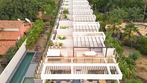 Ein modernes Gebäude mit mehreren Balkonen, einem Pool und üppigem Grün rundherum.