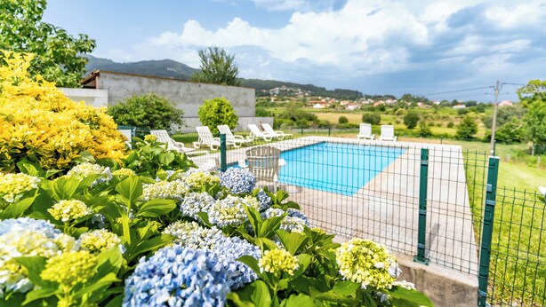 Zona de piscina con valla de alambre, sillas de descanso y vistas al campo.