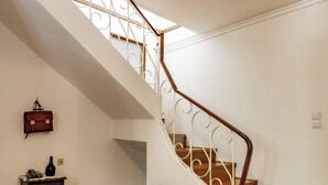 Una escalera con barandilla blanca y una lámpara colgante.