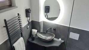 A modern bathroom with a freestanding sink, a toilet, and a bidet.