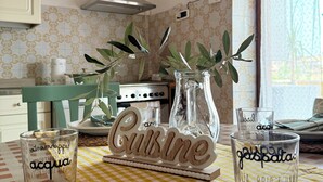 Eine Küche mit kariertem Tischläufer, einem Holzschild mit der Aufschrift 'Cuisine' und zwei klaren Gläsern mit Text.