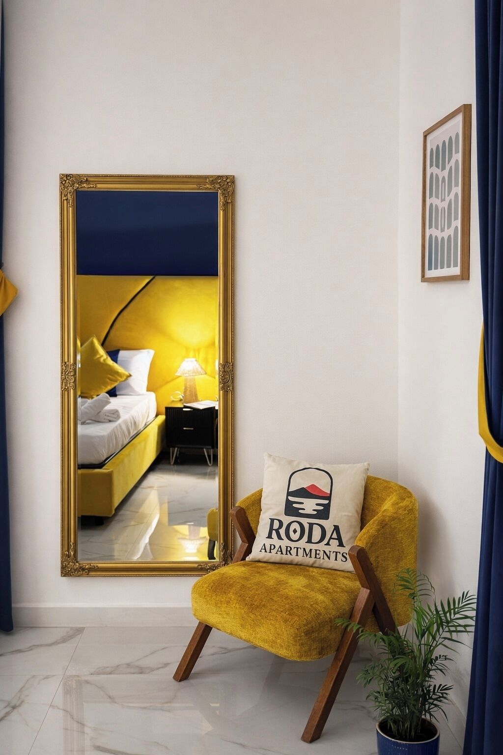 Una habitación con una cama, una mesita de noche, un espejo, un sillón amarillo, una planta en maceta y un cuadro en la pared.
