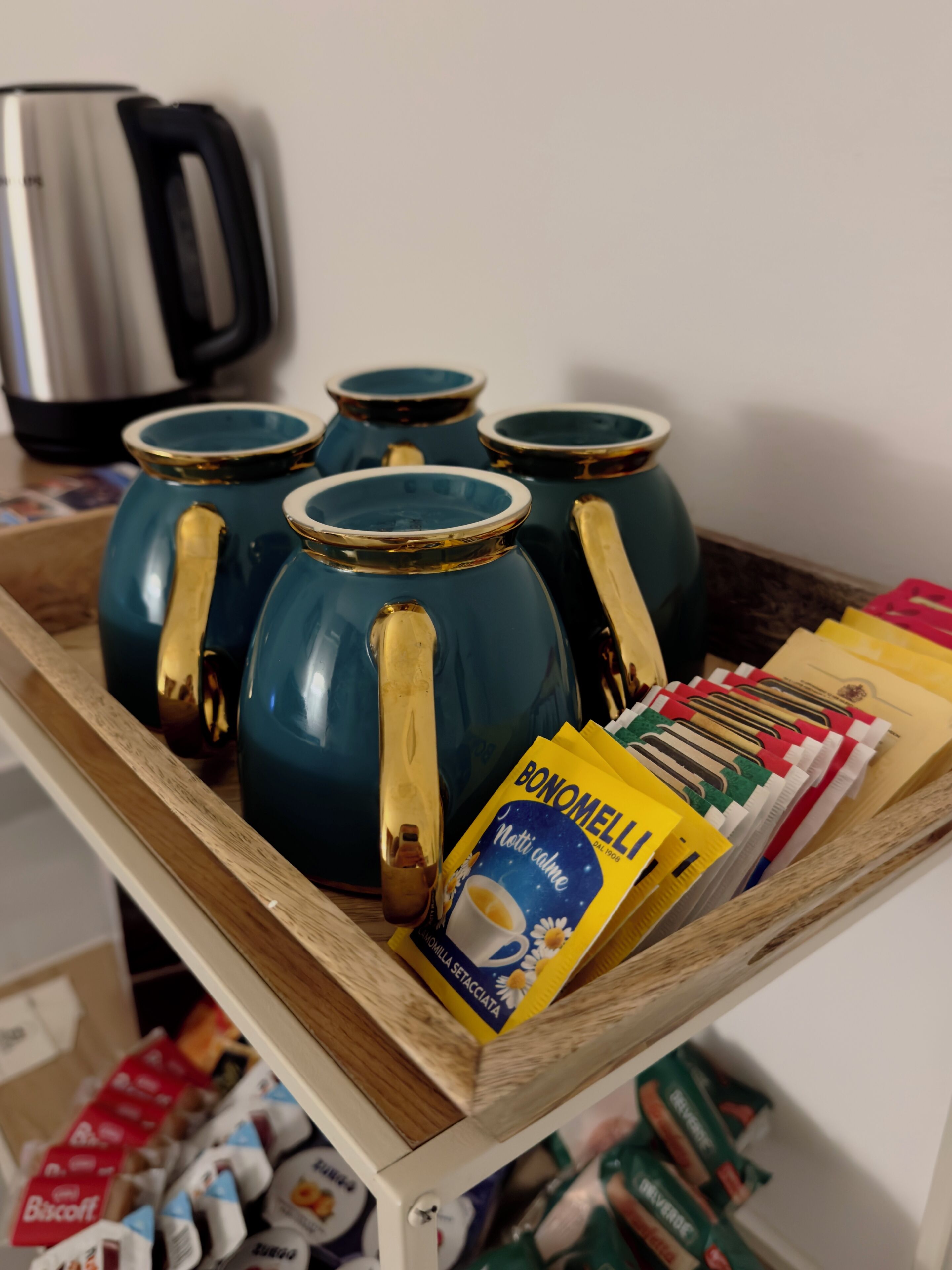 Una encimera de cocina con una cafetera, teteras y cápsulas de café.