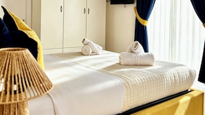 Un lit avec une tête de lit, une table de chevet, une lampe, une télévision et une armoire.