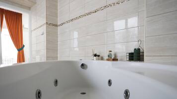 Ein modernes Badezimmer mit einer großen Badewanne, gefliesten Wänden und einem Fenster mit Vorhängen.