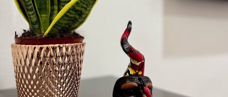 A potted plant with variegated leaves and a small figurine on a table.