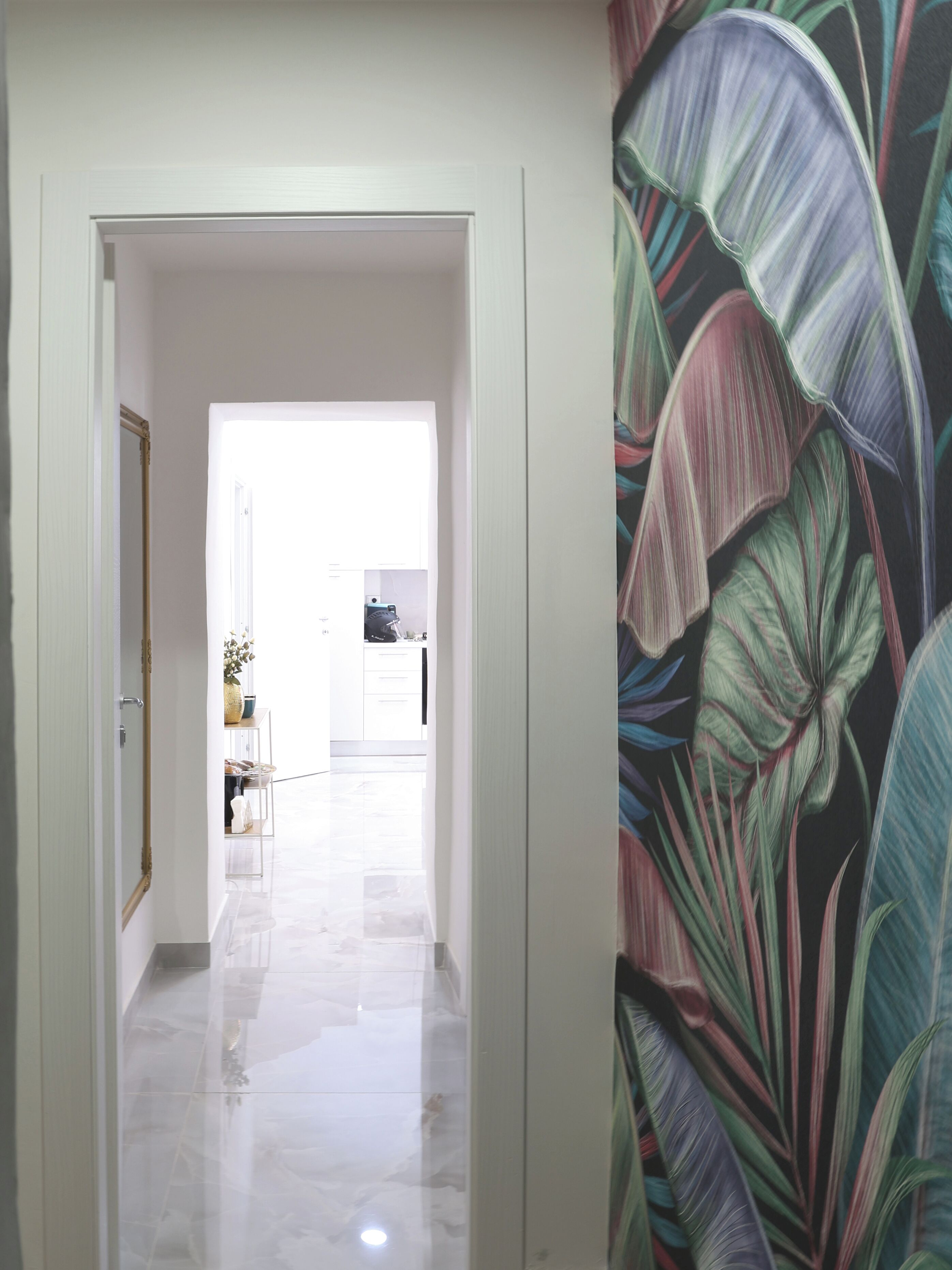 Un pasillo con una puerta blanca que da a una habitación luminosa.
