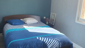 Ein Schlafzimmer mit einem Bett, einem Nachttisch, einer Lampe und einem gerahmten Bild an der Wand.