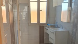 Ein kleines, sauberes Badezimmer mit Toilette, Waschbecken und Fenster.