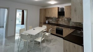 Una cucina moderna con mobili in legno, un piano di lavoro in marmo e un'area pranzo con sedie bianche.