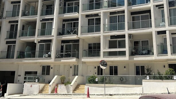 Un edificio residenziale a più piani con balconi, ampie finestre e cielo sereno.