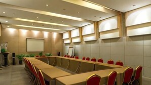 A conference room with a long table, red chairs, and a projector screen. - Jinjiang Inn (Beijing Sanyuanqiao Yansha International Exhibition Center Hotel) (Beijing)