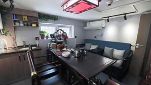 A compact kitchen with a central island, built-in shelves, and a dining area with a blue couch. - Jinjiang Inn (Beijing Sanyuanqiao Yansha International Exhibition Center Hotel) (Beijing)