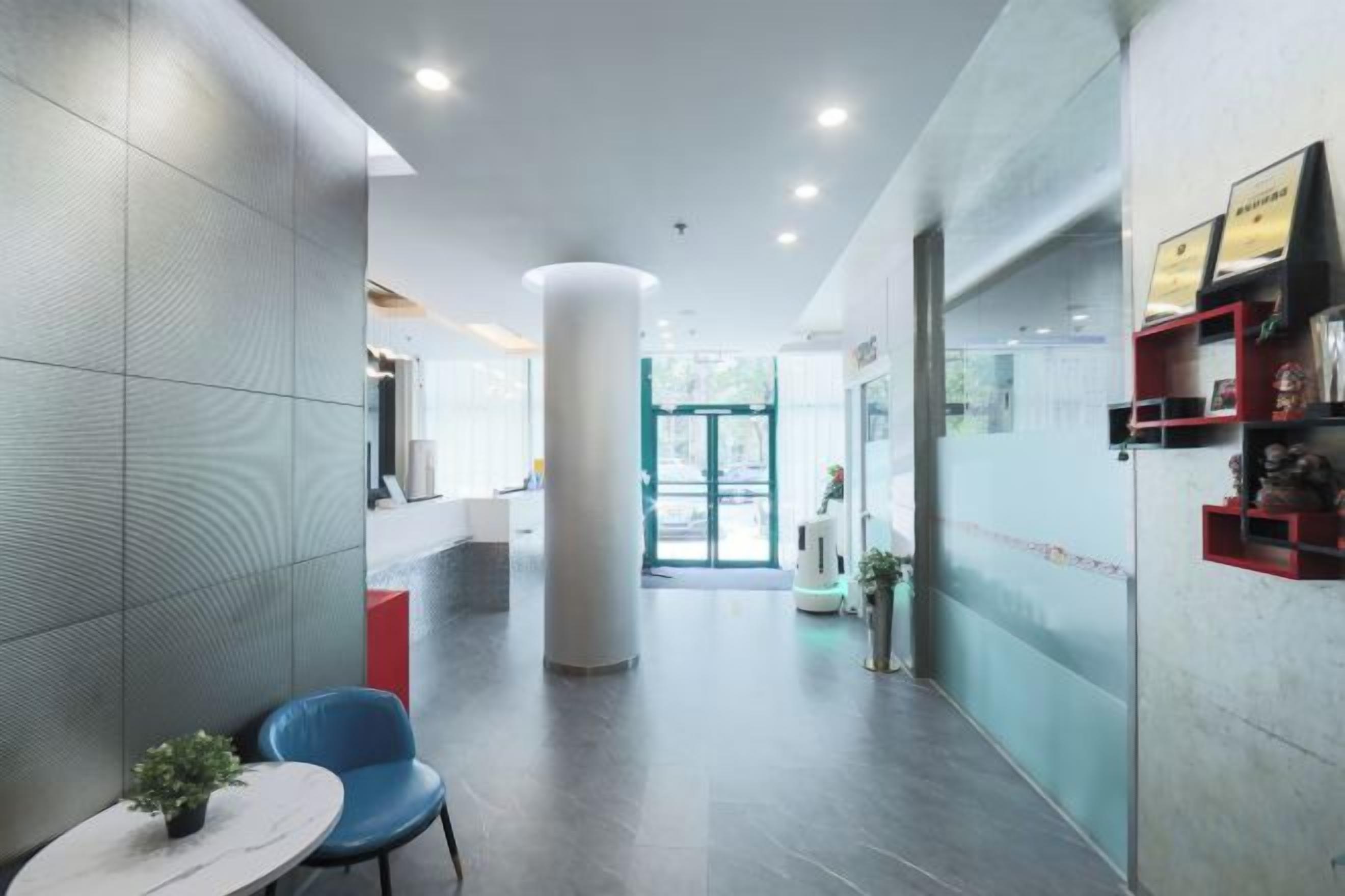 A modern lobby with a reception desk, a blue chair, and a small table with a plant.