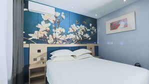 A hotel room with a bed, a wall-mounted air conditioner, a painting, and a shelf. - Jinjiang Inn (Beijing Sanyuanqiao Yansha International Exhibition Center Hotel) (Beijing)