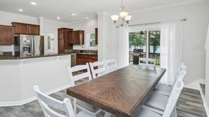 Une cuisine spacieuse équipée d’appareils modernes, un coin repas avec une grande table en bois et une vue sur l’extérieur.