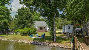 Une propriété au bord du lac comprenant une maison, un quai et un espace extérieur aménagé pour s’asseoir.