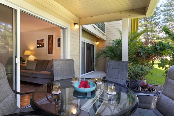 A glass-top table with chairs, a sofa, and a dining table with a bowl and glasses.