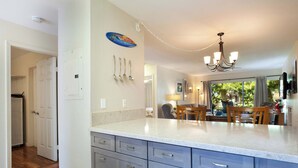 A kitchen with a marble countertop, grey cabinets, and a chandelier.