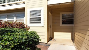 A building entrance with a door, a window, and a small step leading to a porch.