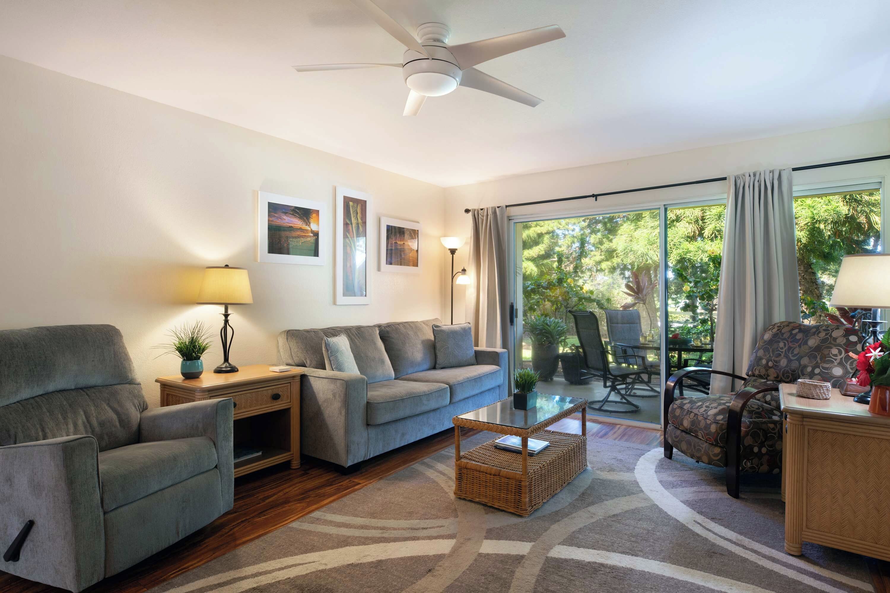 A living room with a sofa, armchairs, a coffee table, and a ceiling fan.