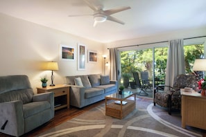 A living room with a sofa, armchairs, a coffee table, and a ceiling fan.
