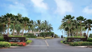 A driveway leading to Waikoloa Colony Villas with palm trees and a clear sky. - Pools, Gym & BBQ, Near Beach & Golf, Tennis (Waikoloa Village)