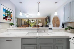 Bright kitchen with marble style counters overlooks living room and garden through pendant lighting.

 - Pools, lanai & BBQ, Beach gear, On Golf Course (Waikoloa Village)