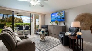 A modern living room with a sofa, armchairs, a coffee table, and a TV mounted on the wall. - Pools, lanai & BBQ, Beach gear, On Golf Course (Waikoloa Village)