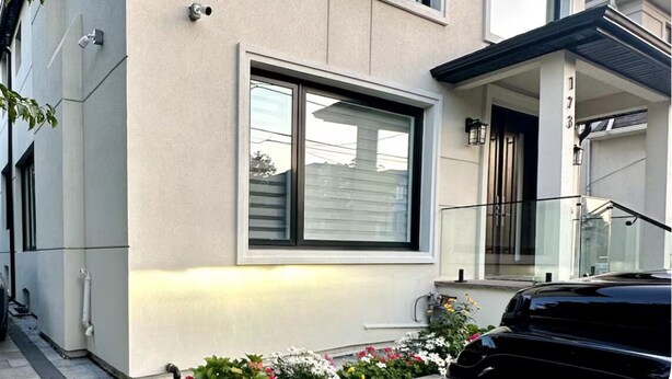 Un edificio de dos pisos con ventanas grandes, un garaje y un número de casa visible.