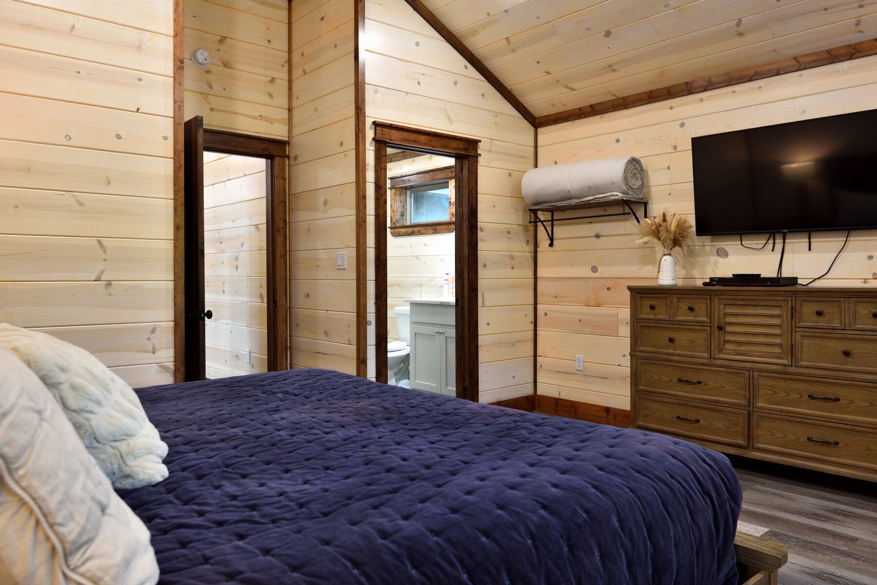 Ein Schlafzimmer mit einem großen Bett, Holzwänden, einem Schminktisch und einem Fernseher.