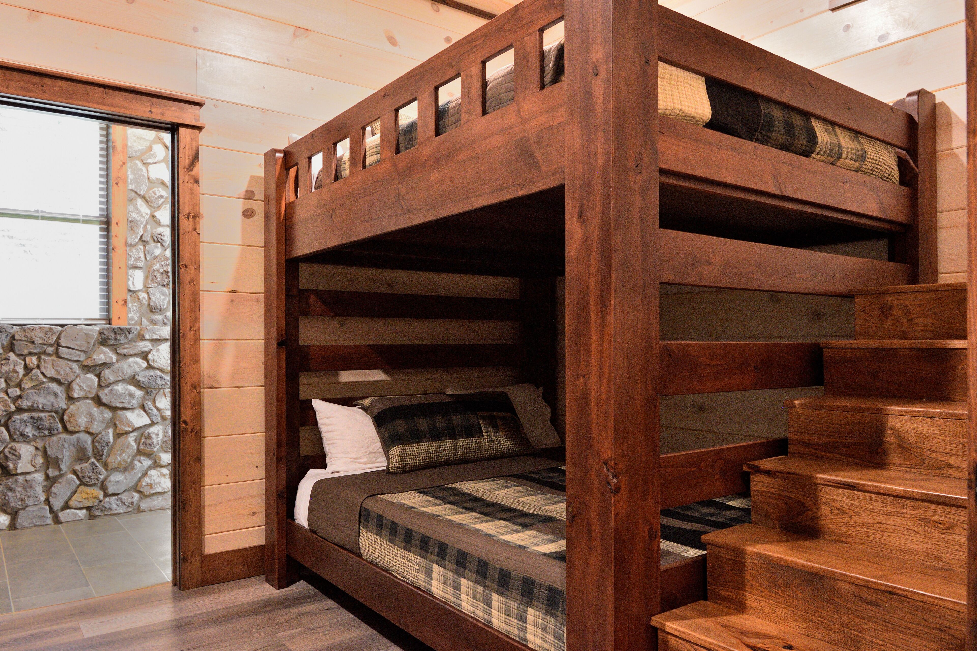 Ein Holzbett mit Etagen, eine Steinsäule und Holzboden.