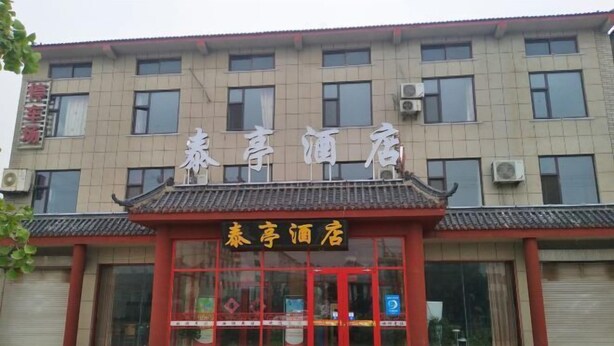 A hotel with a traditional architectural style, featuring a prominent entrance with red doors and a tiled roof. - Song Nantaiting Hotel (Junan County)