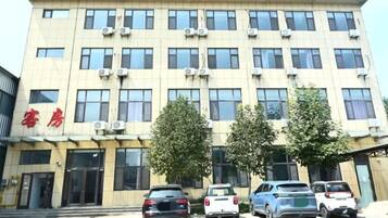 A multi-story building with a row of windows and air conditioning units on the facade.