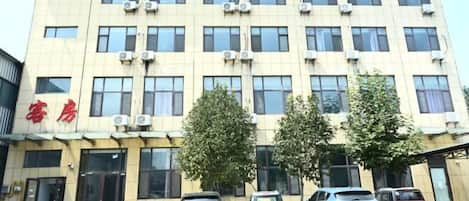 Un edificio de varios pisos con una fila de ventanas y unidades de aire acondicionado en la fachada.